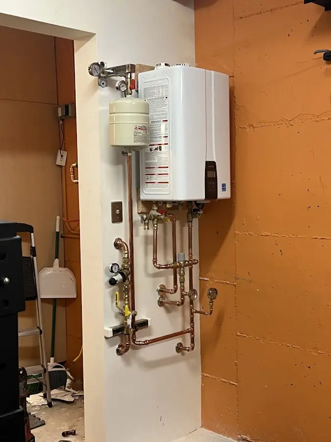 Plumbing technician inspecting water heater connections in Warwick